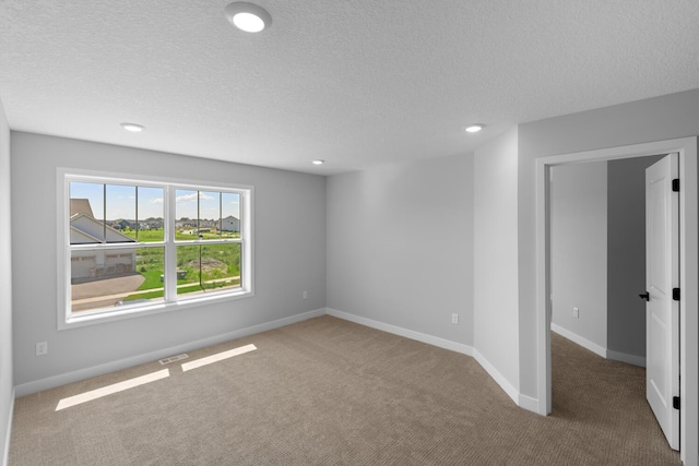 carpeted empty room featuring a textured ceiling, visible vents, and baseboards