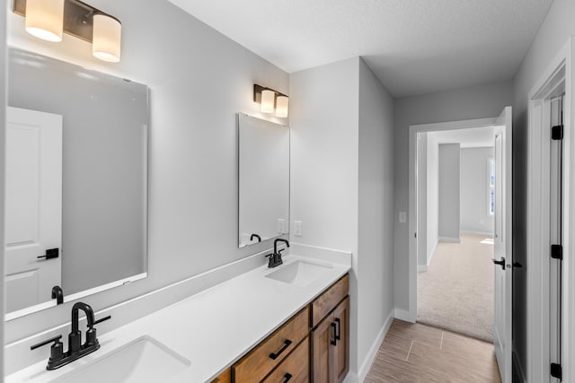 full bath featuring a sink, baseboards, and double vanity