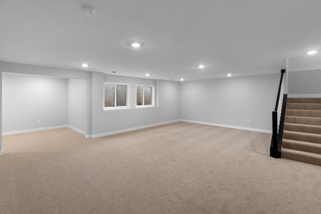 basement featuring recessed lighting, light colored carpet, stairway, and baseboards