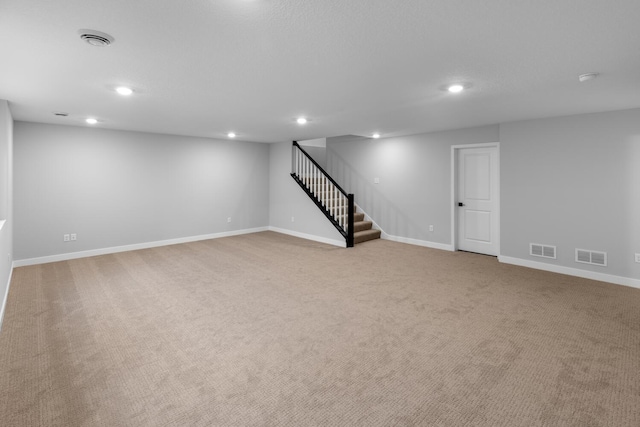 finished below grade area featuring recessed lighting, visible vents, and stairway