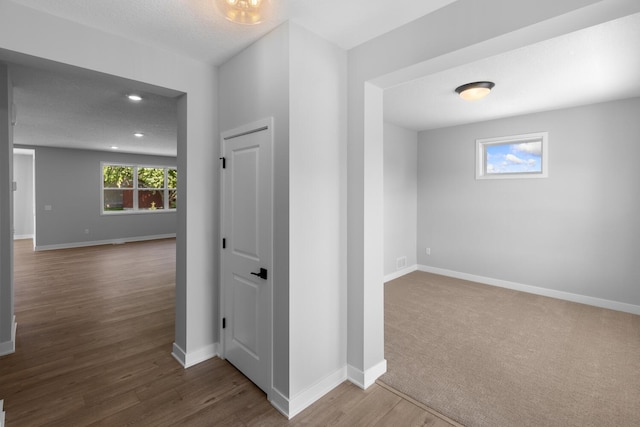 corridor featuring recessed lighting, a textured ceiling, baseboards, and wood finished floors