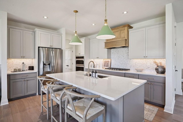 kitchen with a breakfast bar area, gray cabinetry, stainless steel appliances, and dark hardwood / wood-style flooring