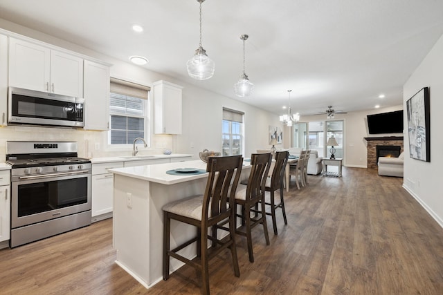 kitchen with white cabinets, stainless steel appliances, a center island, and hanging light fixtures