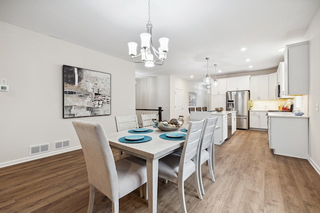 dining area featuring light wood-type flooring and a notable chandelier