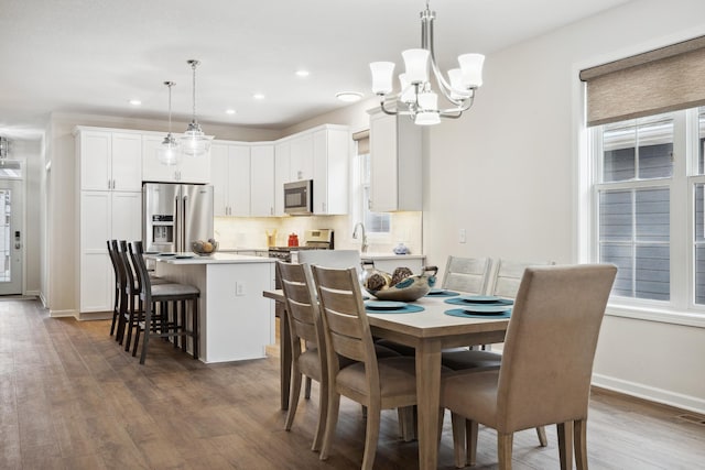 dining space featuring sink, a chandelier, a healthy amount of sunlight, and dark hardwood / wood-style flooring