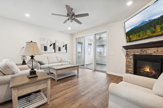 living room featuring ceiling fan, a fireplace, and wood-type flooring