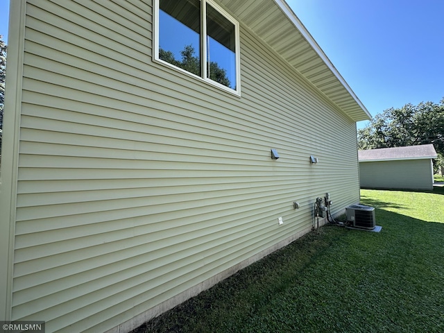 view of side of home with central AC unit and a lawn