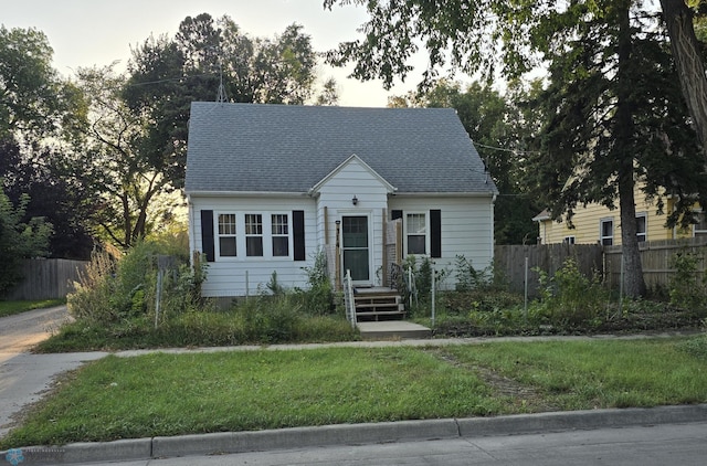 cape cod home featuring a front lawn