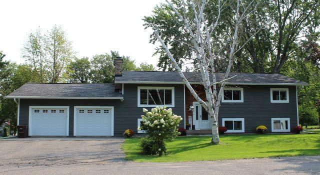 bi-level home with a front lawn, a garage, driveway, and a chimney