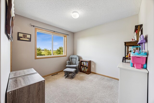 living area featuring light carpet and a textured ceiling