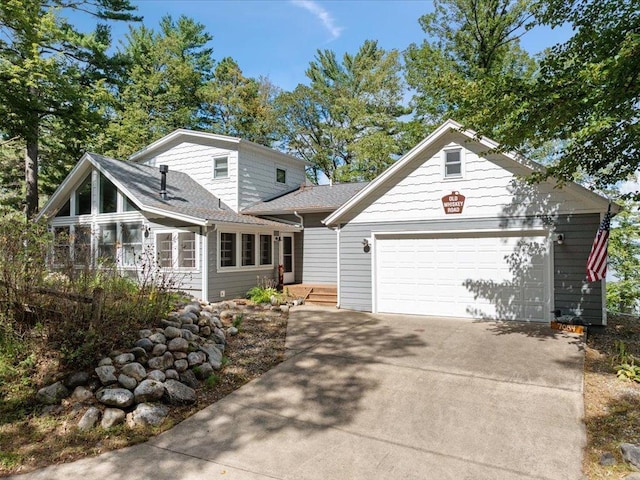 view of front facade featuring concrete driveway, a garage, and a sunroom