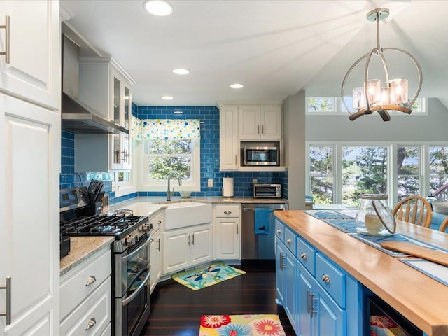 kitchen featuring white cabinets, wooden counters, stainless steel appliances, and a sink