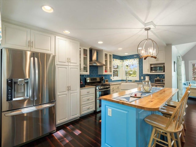 kitchen featuring a sink, stainless steel appliances, white cabinets, wall chimney exhaust hood, and butcher block counters