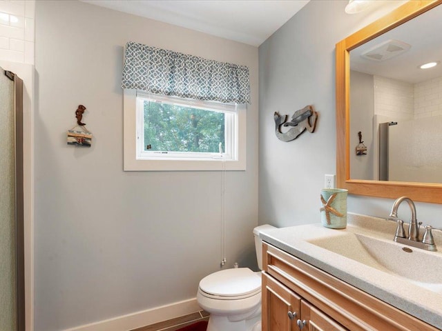 bathroom featuring visible vents, toilet, baseboards, walk in shower, and vanity