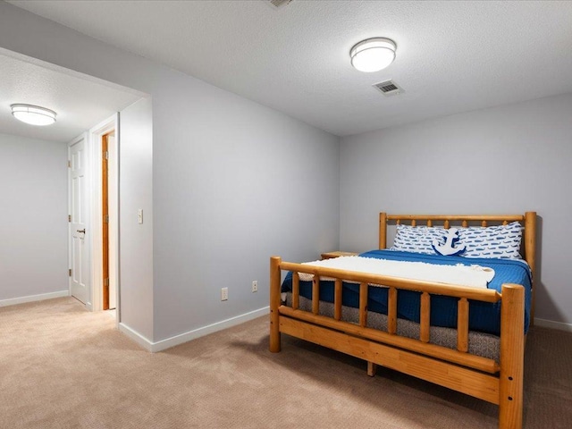 bedroom featuring light colored carpet, baseboards, visible vents, and a textured ceiling