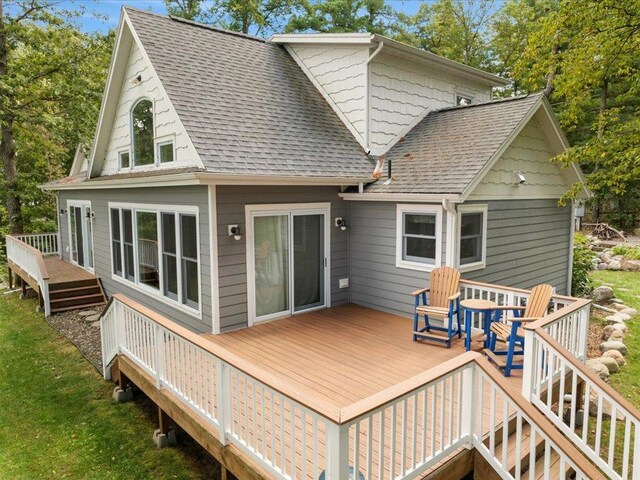 back of property with a wooden deck and roof with shingles
