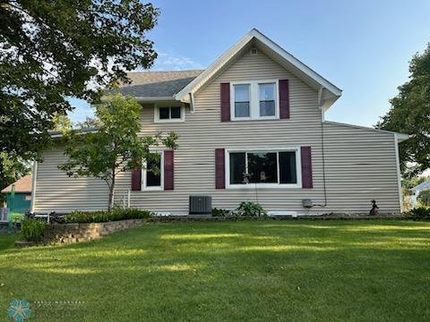 back of property featuring central AC unit and a yard