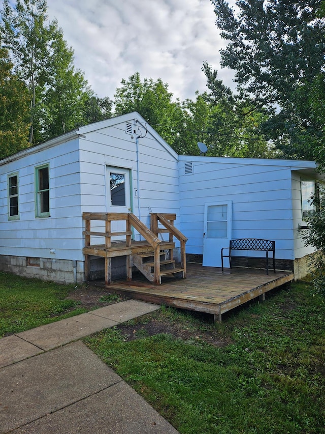 rear view of property with a lawn and a deck