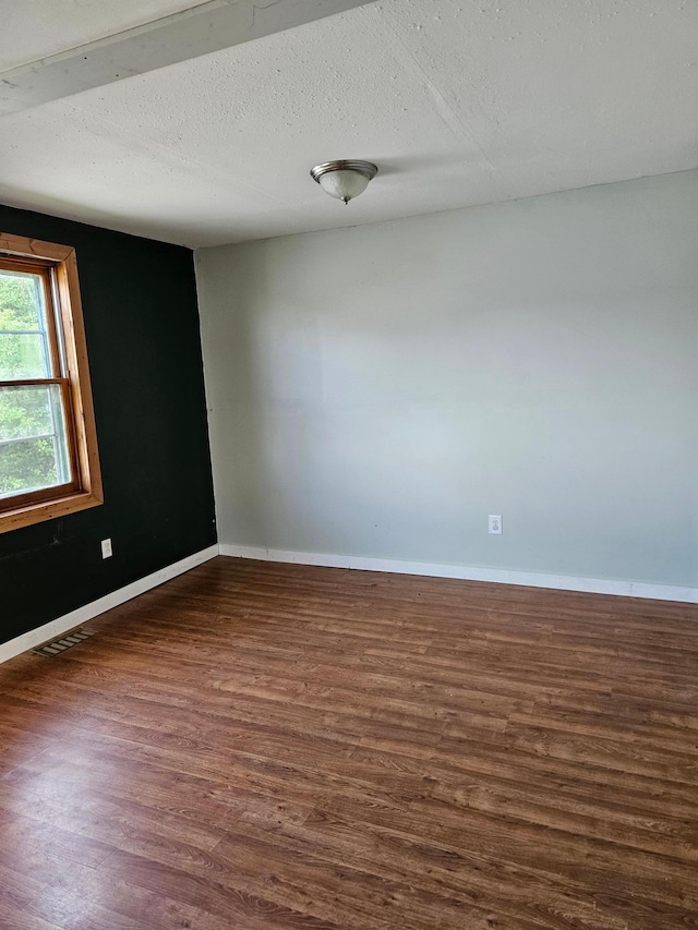 empty room with a textured ceiling and dark hardwood / wood-style flooring