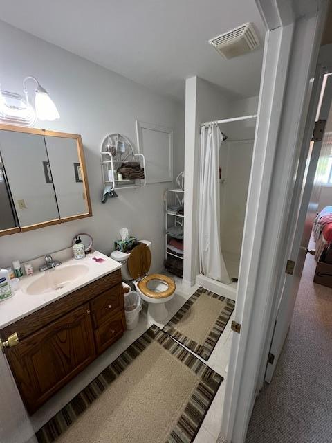 bathroom with walk in shower, toilet, and vanity