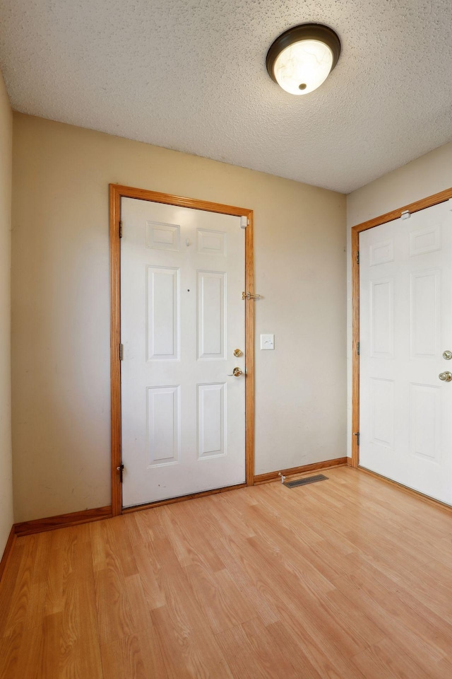 entryway with a textured ceiling and light hardwood / wood-style flooring