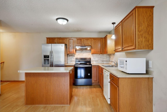 kitchen featuring pendant lighting, white appliances, a kitchen island, a textured ceiling, and light hardwood / wood-style floors