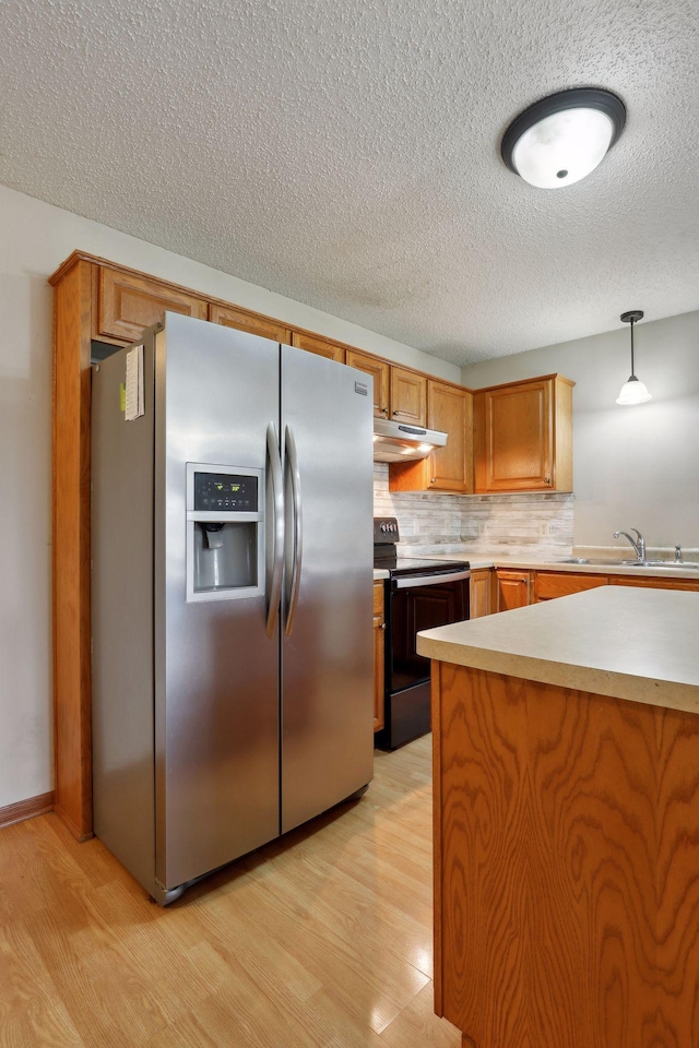 kitchen with hanging light fixtures, stainless steel fridge, light wood-type flooring, and electric range