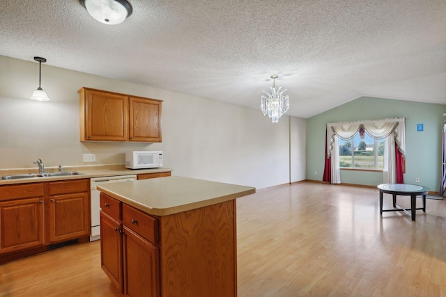 kitchen featuring lofted ceiling, sink, white appliances, decorative light fixtures, and a center island