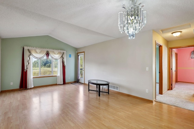 sitting room with an inviting chandelier, lofted ceiling, a textured ceiling, and hardwood / wood-style floors