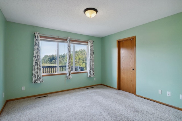 carpeted empty room featuring a textured ceiling