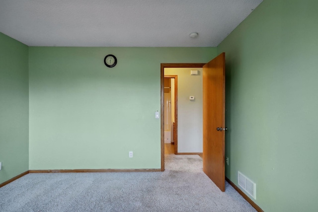 empty room featuring light carpet and a textured ceiling