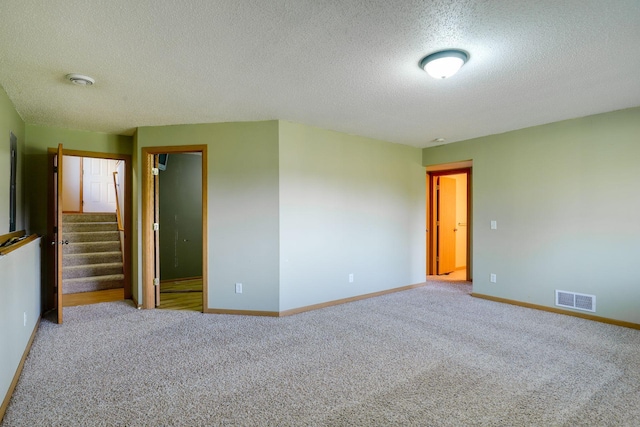 carpeted spare room with a textured ceiling