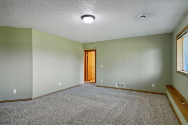 carpeted empty room featuring a textured ceiling