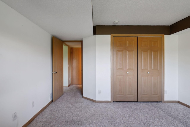 unfurnished bedroom featuring light carpet, a textured ceiling, and a closet