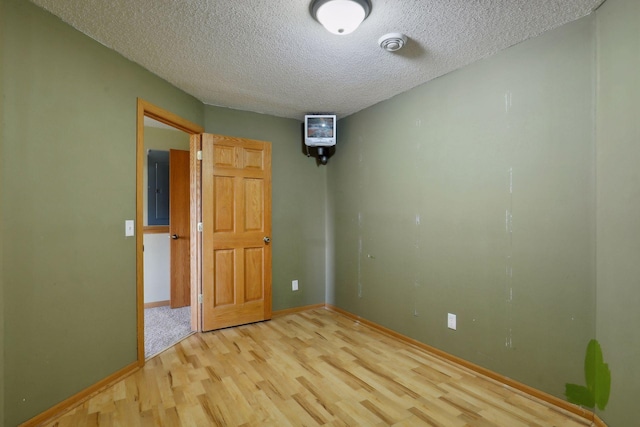 unfurnished bedroom with light hardwood / wood-style flooring, a textured ceiling, and electric panel