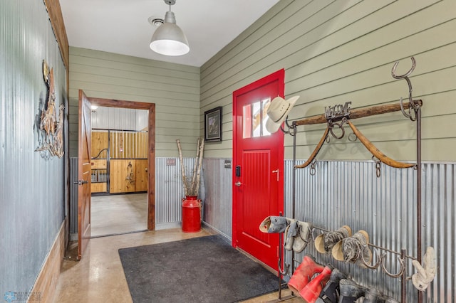 entryway with wood walls and concrete flooring