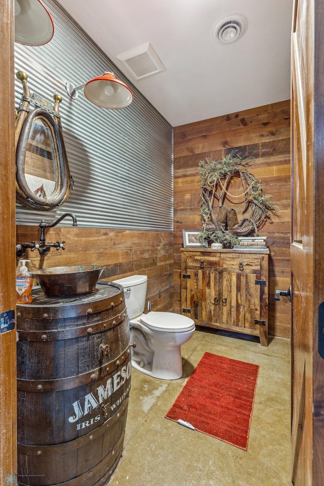 bathroom with vanity, toilet, and wood walls