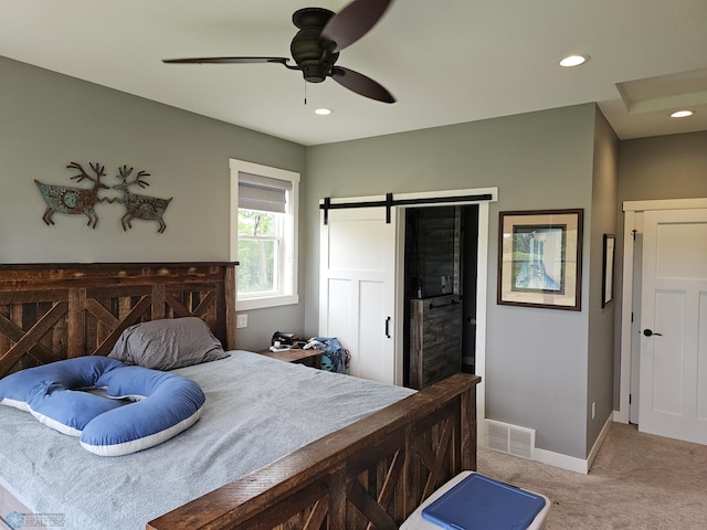 bedroom with carpet, ceiling fan, and a barn door