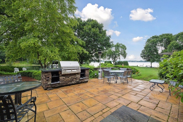 view of patio with outdoor dining area, a water view, area for grilling, and an outdoor kitchen