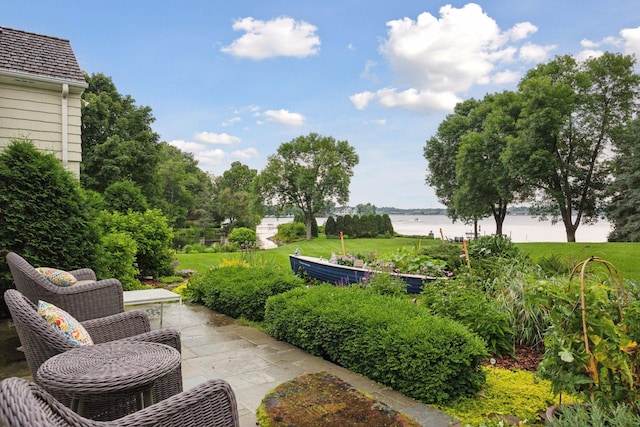 view of home's community with a water view, a vegetable garden, and a patio area