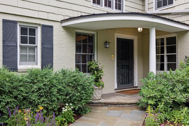 property entrance featuring brick siding and a porch