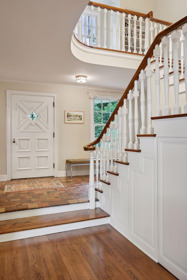 entryway featuring baseboards, wood finished floors, stairs, and ornamental molding