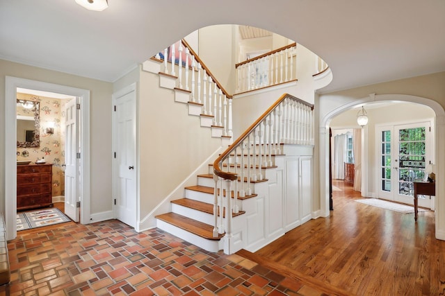 stairway with arched walkways, brick floor, and baseboards