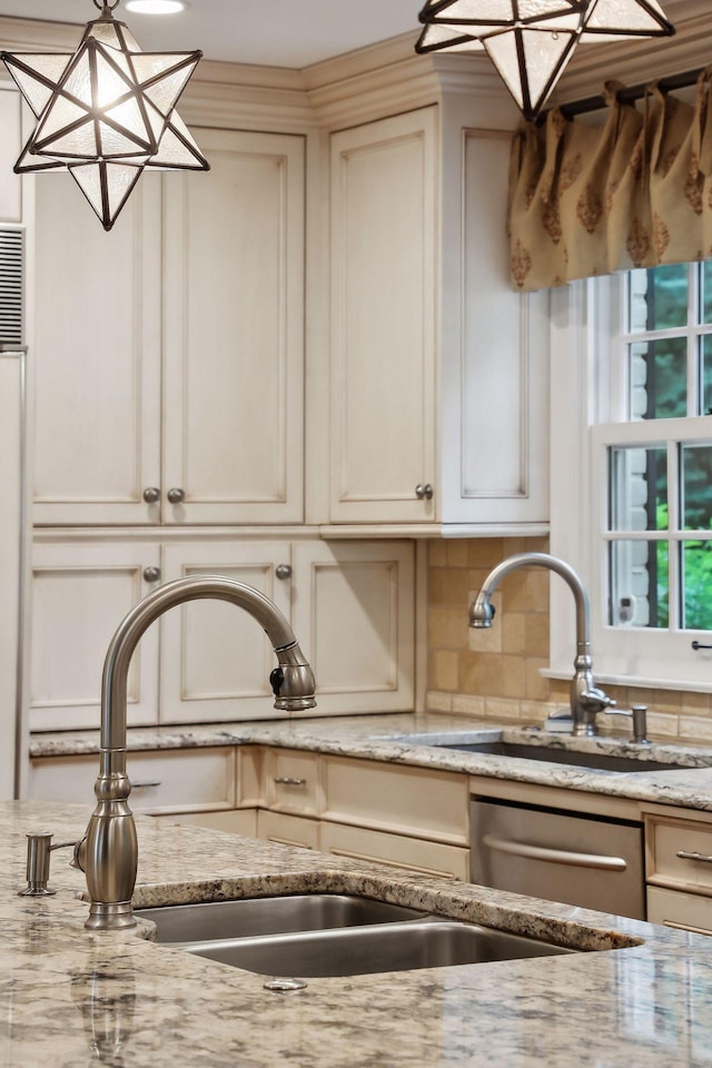 kitchen with light stone countertops, decorative backsplash, stainless steel dishwasher, hanging light fixtures, and a sink