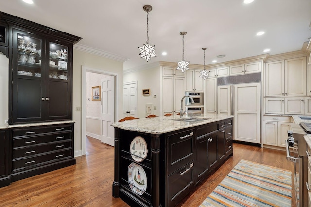 kitchen featuring crown molding, stainless steel oven, wood finished floors, paneled built in refrigerator, and a sink