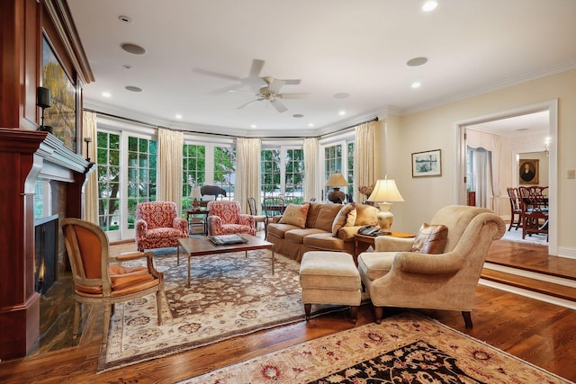 living area with a high end fireplace, plenty of natural light, crown molding, and wood finished floors