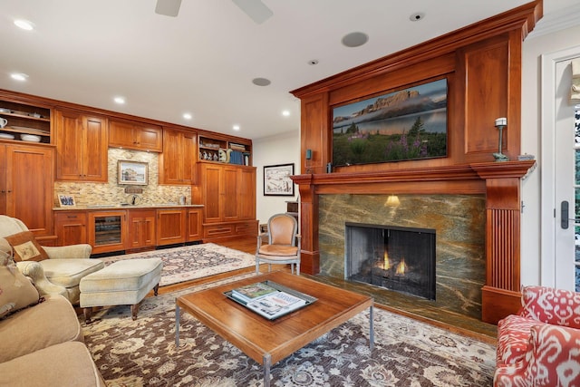 living area with a high end fireplace, beverage cooler, ornamental molding, recessed lighting, and wood finished floors