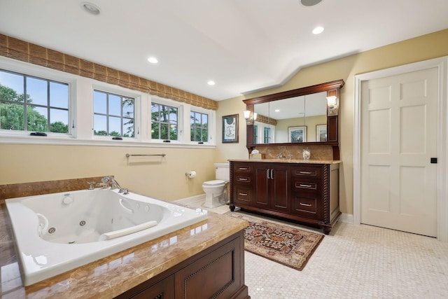 bathroom featuring a tub with jets, recessed lighting, vanity, and toilet