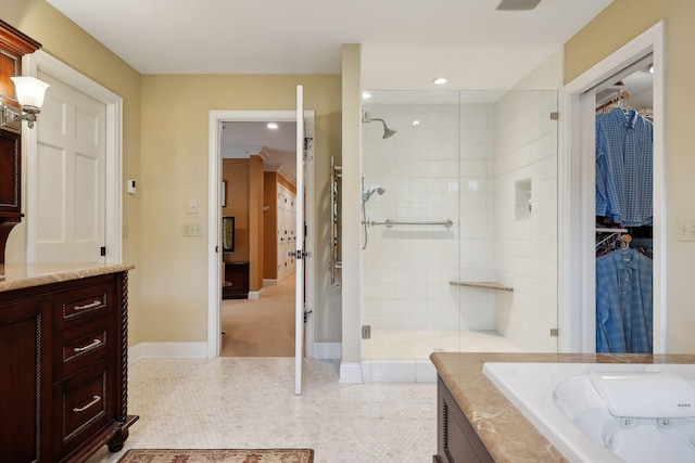 bathroom featuring tile patterned flooring, a walk in closet, a tub with jets, and a stall shower