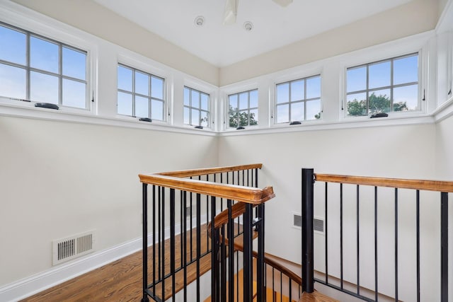 stairs featuring a wealth of natural light, visible vents, baseboards, and wood finished floors